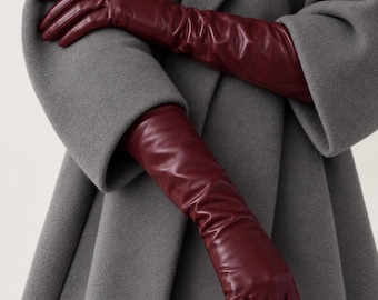 May include: A pair of long, deep burgundy leather gloves that extend past the wrist, featuring a smooth, fitted construction with visible stitching along the fingers and a soft, slightly gathered texture along the forearm.
