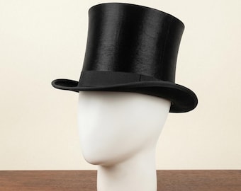 May include: A black top hat with a wide brim and a black band. The hat is displayed on a white mannequin head. The hat is a classic formal accessory.