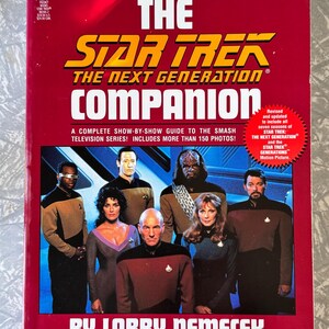 Puede incluir: Una portada de libro roja para "The Star Trek: The Next Generation Companion" con el logotipo del programa en amarillo y blanco. La portada presenta imágenes del elenco y el nombre del autor, Larry Nemecek.