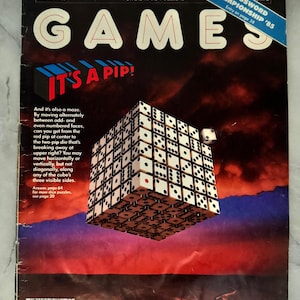 May include: A vintage Games magazine cover from March 1985, featuring a 3D cube puzzle with dice. The cover has the text "IT'S A PIP!" and "CROSSWORD CHAMPIONSHIP '85". The background is a gradient of red, orange, and blue.