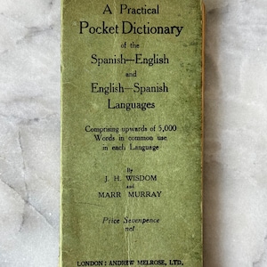 Peut inclure: Un petit dictionnaire de poche vert vintage. La couverture indique "A Practical Pocket Dictionary of the Spanish-English and English-Spanish Languages." Le texte est noir, avec les auteurs J. H. Wisdom et Marr Murray. Publié par Andrew Melrose, Ltd.