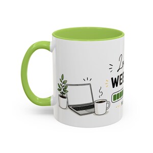 Op de afbeelding: Een witte keramische mok met een limoengroene handgreep en binnenrand. De buitenkant is voorzien van een grafische illustratie van een potplant, een open laptop en een dampende koffiemok, naast de tekst "LOADING WEEKEND" met een groene voortgangsbalk.