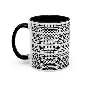 Puede incluir: Una taza de cerámica blanca con interior y asa de color negro. La superficie exterior presenta un patrón repetitivo de bandas horizontales que contienen varias formas geométricas negras, incluyendo círculos, líneas, cuadrados y semicírculos.