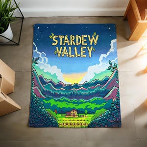Pu&ograve; includere: Una coperta rettangolare con un'illustrazione colorata di un paesaggio e la scritta "STARDEW VALLEY". Il design include montagne, una casa, girasoli e un cielo blu con nuvole. La coperta &egrave; probabilmente in tessuto morbido.