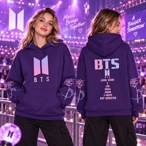 Pode incluir: Uma camisola com capuz roxa escura com o logótipo BTS num gradiente rosa e azul na parte da frente. A parte de trás apresenta o logótipo BTS, o texto BTS e os nomes Jung Kook, V, Jin, Suga, Jimin, J-Hope e Rap Monster em branco.