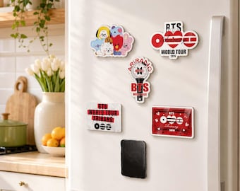 May include: Five decorative magnets on a white refrigerator door. One features colorful cartoon characters, another is a red and white BTS World Tour 2026 logo, a light stick shaped magnet, a rectangular BTS World Tour Arirang sign, and a red cassette.