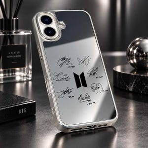 Op de afbeelding: Een zilverkleurige smartphonehoes met een reflecterend, spiegelend achterpaneel. In het midden staat een zwart BTS-logo omringd door zeven afzonderlijke zwarte handtekeningen, elk gelabeld met de naam van het lid in kleine zwarte letters.