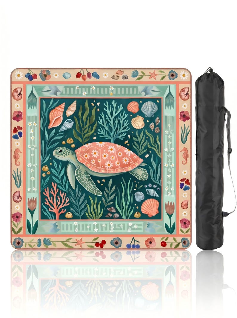 May include: A square beach mat featuring a sea turtle design with coral, seashells, and aquatic plants. The turtle has a pink shell with a floral pattern. The mat is surrounded by a decorative border and comes with a black carrying bag.
