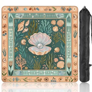 Puede incluir: Una manta de picnic cuadrada con un dise&ntilde;o de concha y perla. La manta presenta una imagen central de una concha abierta con una perla, rodeada de otras conchas, coral y algas marinas. El borde es un patr&oacute;n floral en melocot&oacute;n y verde azulado. Se incluye una bolsa de transporte negra.