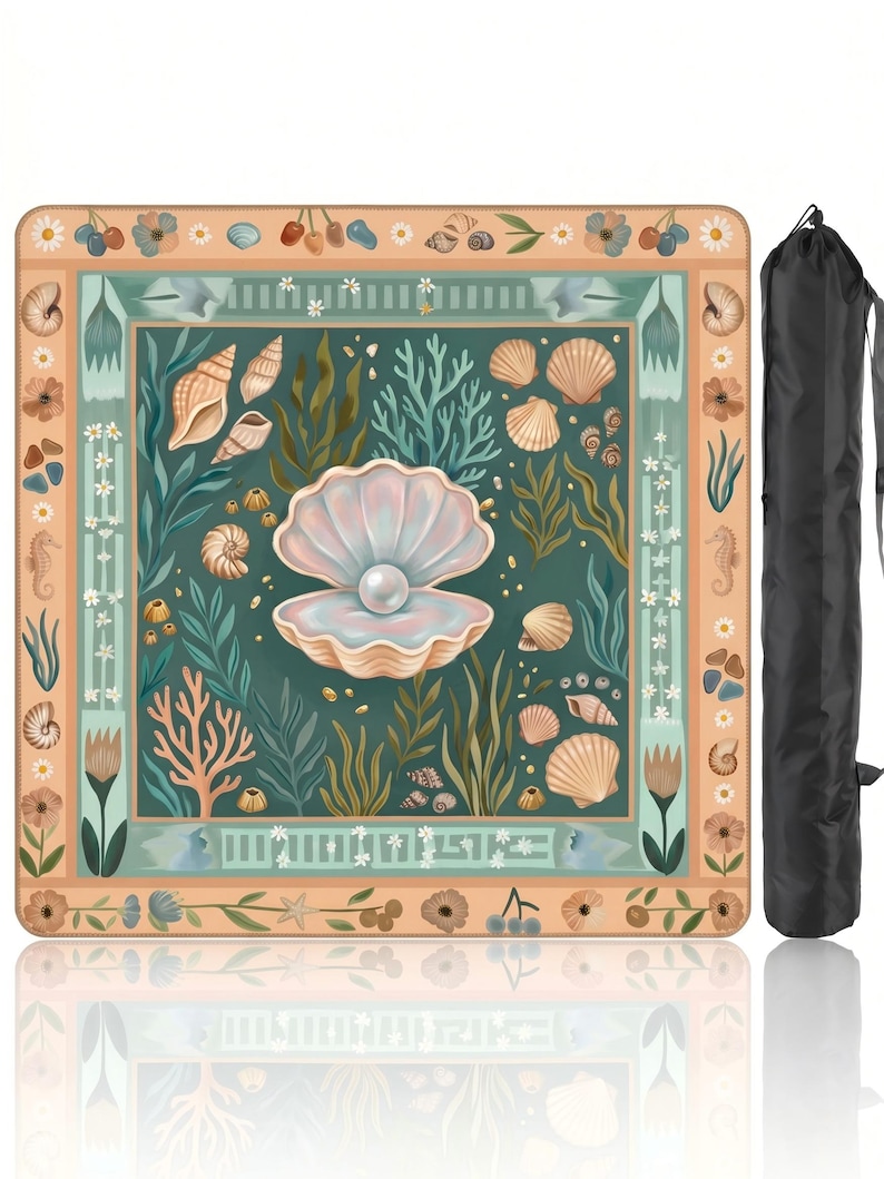 Puede incluir: Una manta de picnic cuadrada con un dise&ntilde;o de concha y perla. La manta presenta una imagen central de una concha abierta con una perla, rodeada de otras conchas, coral y algas marinas. El borde es un patr&oacute;n floral en melocot&oacute;n y verde azulado. Se incluye una bolsa de transporte negra.