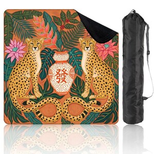 May include: A yoga mat featuring a vibrant design with two cheetahs, a vase with Chinese characters, and tropical foliage in shades of orange, green, and pink. Includes a black carrying bag.