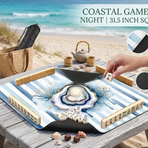 May include: A Mahjong game set with a coastal theme, set on a wooden table. The 80 cm square game board has blue and white stripes and an oyster design. Accessories include wooden tiles, a teapot, cups, and seashells. The text "COASTAL GAME NIGHT" is visible.
