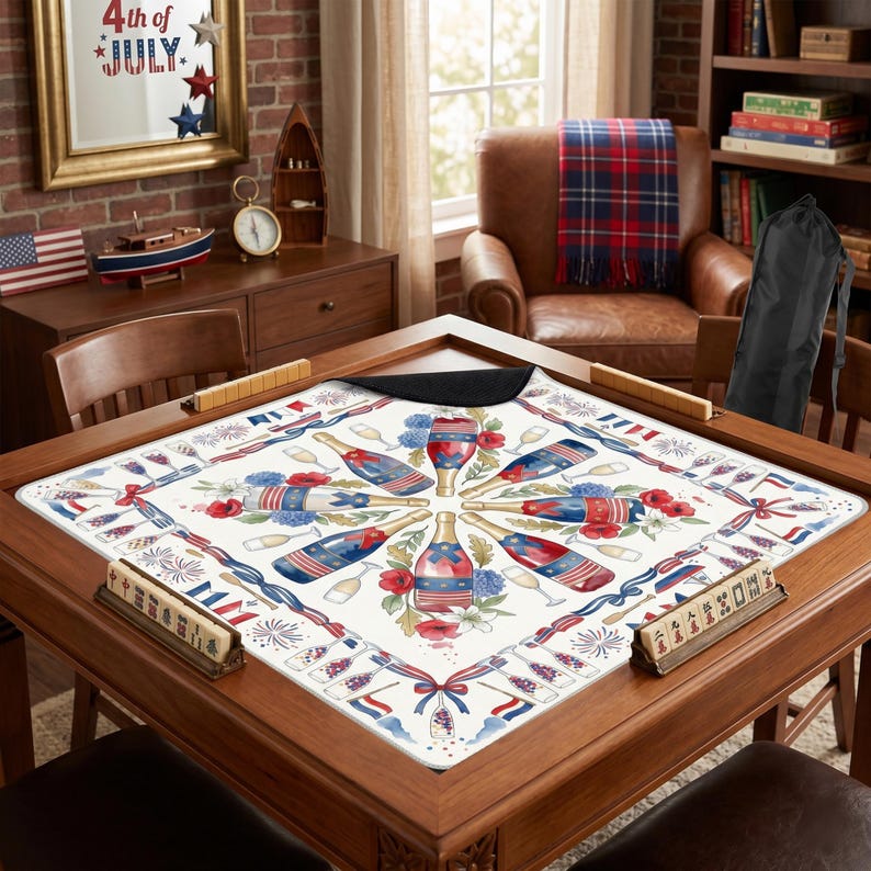 K&ouml;nnte beinhalten: Ein Spieltisch aus Holz mit einer dekorativen Matte mit einem patriotischen Design aus Champagnerflaschen, Feuerwerk und floralen Elementen in Rot, Wei&szlig; und Blau. Der Tisch ist von St&uuml;hlen und anderen dekorativen Gegenst&auml;nden umgeben.