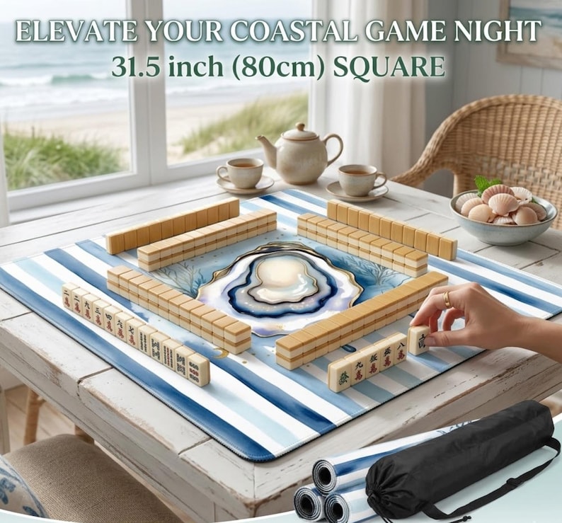 May include: A square Mahjong game mat, 80cm, with a blue and white striped design. The mat features a coastal theme with an oyster shell design in the centre. The image includes Mahjong tiles, a teapot, and teacups.