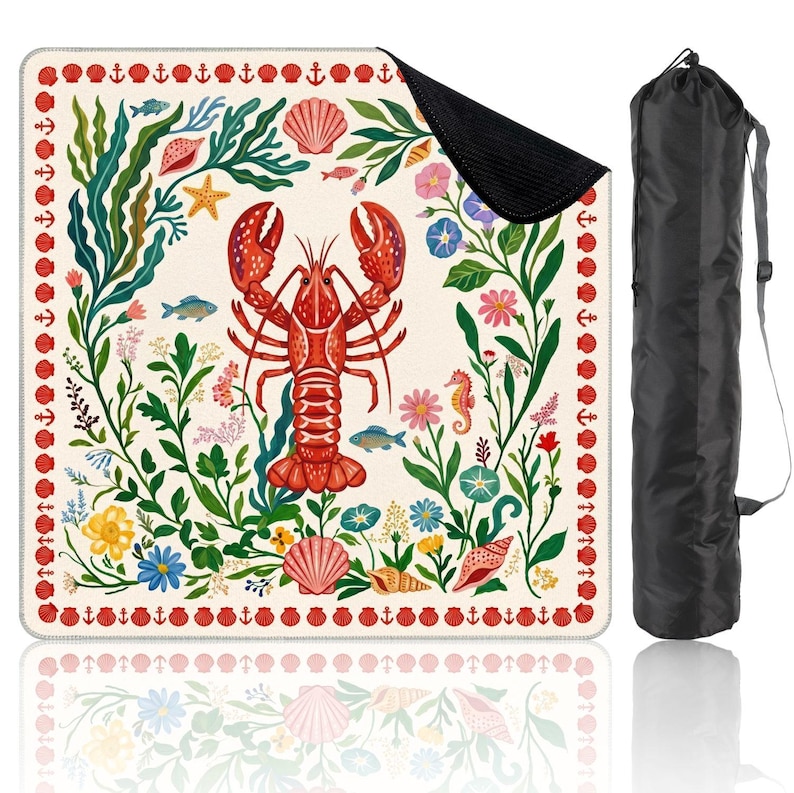 Puede incluir: Una manta de playa cuadrada con un dise&ntilde;o de langosta y vida marina. La manta presenta una langosta roja, conchas marinas, estrellas de mar y peces, rodeados de algas verdes y flores coloridas. Se incluye una bolsa de transporte negra.
