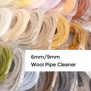 May include: Assortment of colorful wool pipe cleaners in various shades, including white, yellow, pink, and orange. The image shows multiple packages of the 6mm/9mm pipe cleaners, ideal for craft projects.