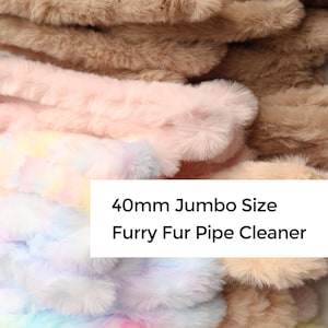 May include: A stack of 40mm jumbo-sized furry fur pipe cleaners in various colors, including brown, tan, pink, and pastel rainbow hues. The image shows the soft, fluffy texture of the craft supplies.