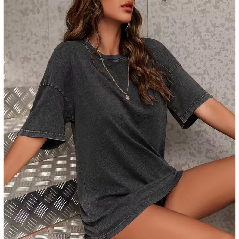 A woman wearing a gray t-shirt and sitting on a metal bench.