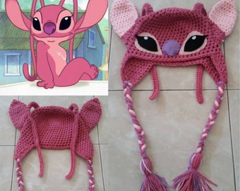 May include: Pink crocheted Stitch hat with long braided ties. The hat features a pink and purple face with black eyes and a purple nose.