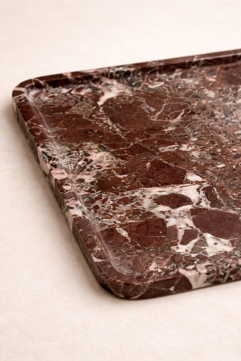 May include: A rectangular serving tray with a raised edge, made from polished red marble. The marble has a complex pattern of dark red, white, and grey veining, creating a luxurious aesthetic. Suitable for serving food or displaying decorative items.