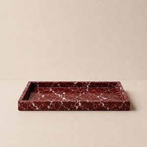 May include: A rectangular tray featuring a deep burgundy red base color with prominent white veining throughout the surface. The tray has a smooth, polished finish and raised edges, creating a structured, open container for various small items.