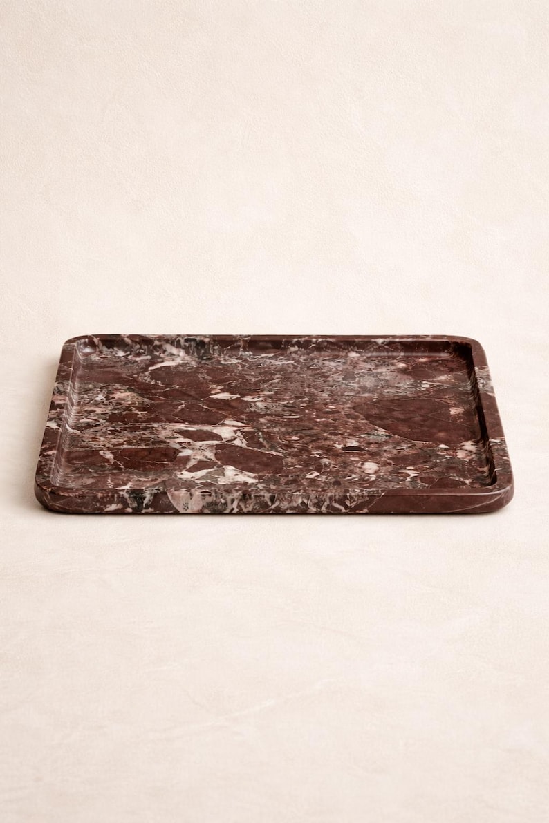 May include: A rectangular serving tray made of red marble with white veining. The tray has a slightly raised edge and rounded corners. This decorative tray is suitable for serving food or displaying items.