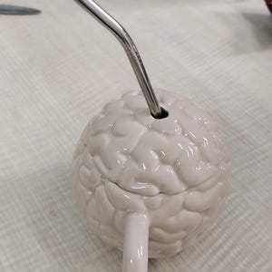 Realistisk keramisk mugg med lock och sugrör, anatomisk kaffekopp