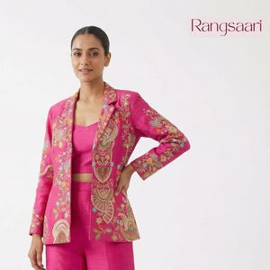 May include: A vibrant pink three-piece outfit featuring a blazer, crop top, and wide-leg pants. The blazer and pants are adorned with intricate floral embroidery in gold, green, and other colors. The outfit is from the brand Rangsari.