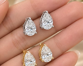 May include: Two pairs of pear-shaped stud earrings, one set in silver-toned metal and the other in gold-toned metal. Each earring features a single clear, faceted stone held by small prongs, creating a classic and elegant jewelry design.