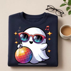 May include: Navy blue sweatshirt featuring a cartoon ghost wearing red sunglasses and holding a disco ball. The ghost is surrounded by stars and musical notes. A fun, colorful design for Halloween or a party.