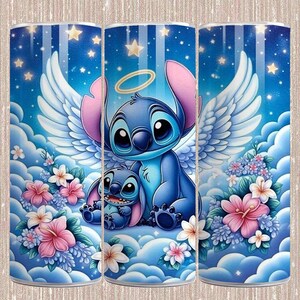 May include: A tumbler featuring a blue cartoon character with large eyes, angel wings, and a halo, accompanied by a smaller version of itself. The design is set against a blue sky with clouds, stars, and floral accents in pink and white.