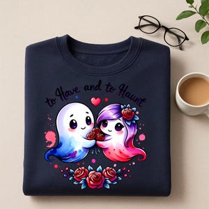 May include: Navy blue sweatshirt with a graphic of two cartoon ghosts holding roses, with the text "to Have and to Haunt". The ghosts are blue and pink, with a heart above them and roses below.