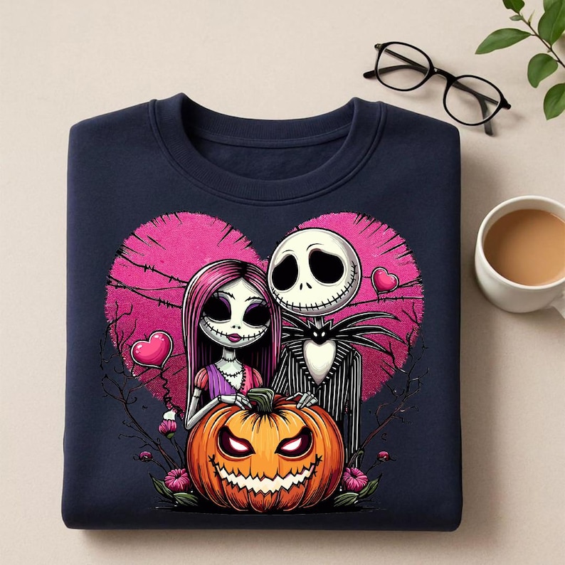 May include: Navy blue sweatshirt featuring a Halloween-themed design. The graphic includes a couple with a pumpkin, set against a pink heart backdrop. The pumpkin has a carved face. The design is a cartoon style.