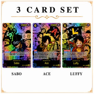 May include: A three-card set featuring Sabo, Ace, and Luffy from the One Piece anime. Each card has a character illustration, a 6-star rating, and a 7000 power level. The cards have colorful backgrounds and Japanese text.