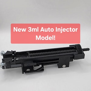 Puede incluir: Un dispositivo autoinyector negro impreso en 3D con un mecanismo de cremallera y piñón, perillas de ajuste de metal plateado y un pequeño perno de metal. El texto New 3ml Auto Injector Model! aparece en blanco sobre un fondo rojo.