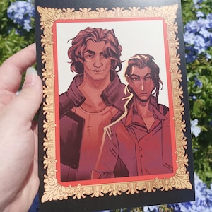 Puede incluir: Una postal negra con una ilustración de dos personas con cabello oscuro. La obra de arte está enmarcada con un borde dorado y rojo ornamentado. El fondo es una mezcla de follaje verde y azul.