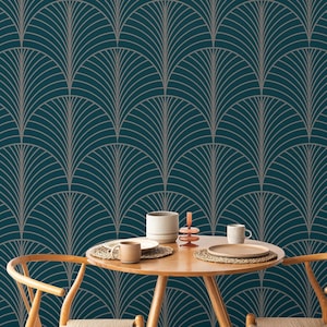 May include: Teal wallpaper with a repeating Art Deco fan pattern in gray. A round wooden table with two chairs is set with mugs, plates, and a candle holder. The scene suggests a dining or living room setting.