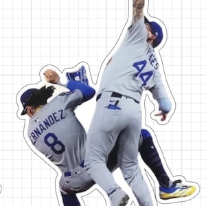 Puede incluir: Dos jugadores de béisbol con uniformes grises y azules saltan en el aire. Uno, con el número 44, extiende un guante rojo. El otro tiene el número 8 en la espalda. Ambos llevan gorras azules.