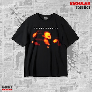May include: A black short-sleeve t-shirt featuring the white text SOUNDGARDEN above a blurry, glowing orange and yellow abstract graphic. The shirt has a crew neckline and a standard fit, with the brand logo Good Root printed inside the neck.