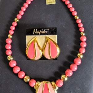 Pu&ograve; includere: Un set di collana e orecchini rosa e oro con un design geometrico. La collana &egrave; realizzata con perline rosa con accenti dorati e un grande ciondolo geometrico. Anche gli orecchini sono geometrici e presentano accenti rosa e oro. Il set &egrave; etichettato "Napier Original".