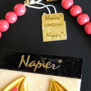 Pu&ograve; includere: Una collana rosa e oro con una chiusura dorata e un'etichetta che recita "Napier Original Napier".