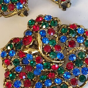 Pode incluir: Um par de brincos em tom dourado com um design de borboleta. As borboletas s&atilde;o cobertas com strass vermelhos, azuis e verdes.