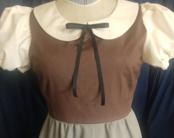 May include: A brown and gray dress with a white collar and a black bow. The dress has short sleeves with puffed shoulders.