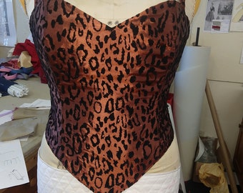 May include: A brown and black leopard print corset with a sweetheart neckline and adjustable straps. The corset is on a white dress form.