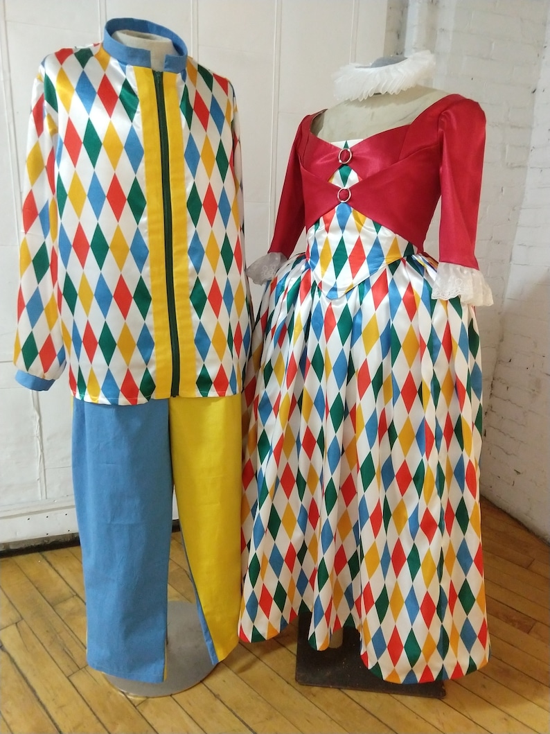 May include: A red and white harlequin costume with a diamond pattern. The costume includes a jacket, pants, and a skirt. The jacket has a yellow zipper and a green stripe down the front. The pants are blue and yellow. The skirt is red, white, blue, green, and yellow.