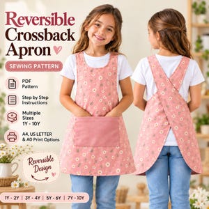 May include: A reversible crossback apron sewing pattern featuring a pink fabric with a white daisy print. The apron has a front pocket and a crossback design. Text includes Reversible Crossback Apron, Sewing Pattern, PDF Pattern, Step by Step Instructions, Multiple Sizes 1Y-10Y, A4, US Letter & A0 Print Options, and Reversible Design.