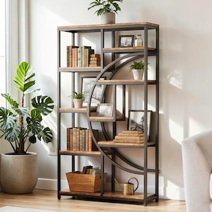 May include: A tall, rectangular bookcase with a dark metal frame and wooden shelves. The unit features a prominent circular metal accent integrated into the right side. It is filled with various books, framed pictures, small potted plants, a woven basket, and a brass watering can.