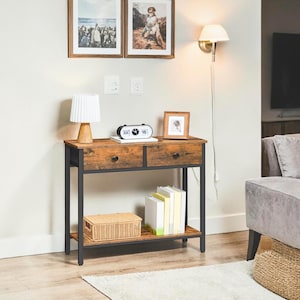 May include: A rustic console table with two drawers and a lower shelf. The table has a dark metal frame and a distressed wood finish. A woven basket, books, and a small clock are on the shelves. Two framed pictures hang above the table.