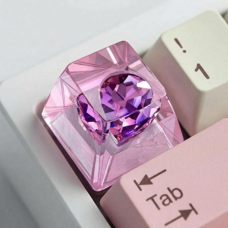 A custom keyboard keycap with a faceted, transparent pink casing. Inside, a purple, gem-like centerpiece is visible.