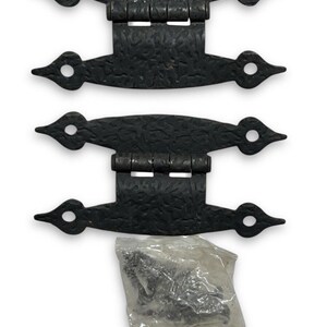 Puede incluir: Juego de tres bisagras decorativas negras con una superficie texturizada y un diseño puntiagudo único. Cada bisagra tiene un agujero circular en el extremo. Se incluye una pequeña bolsa de tornillos.